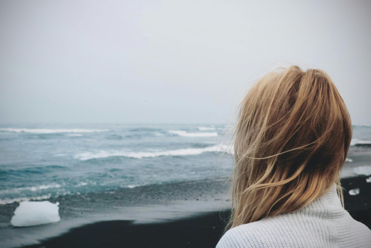 nainen myrskyisän meren rannalla. Kuva:Tiana, Pexels